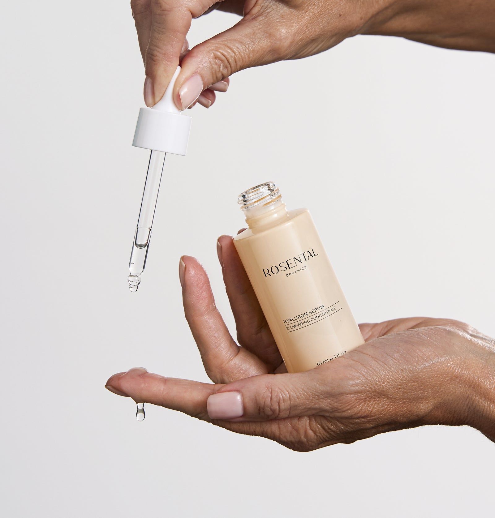 Hände halten eine Flasche und eine Pipette. Flasche mit Aufschrift: ROSENTAL, Hyaluron Serum. Pipette tropft.