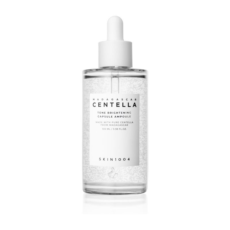 Klare Glasflasche mit weißem Deckel und Etikett. Text: MADAGASCAR CENTELLA, Tone Brightening Capsule Ampoule, SKIN1004.