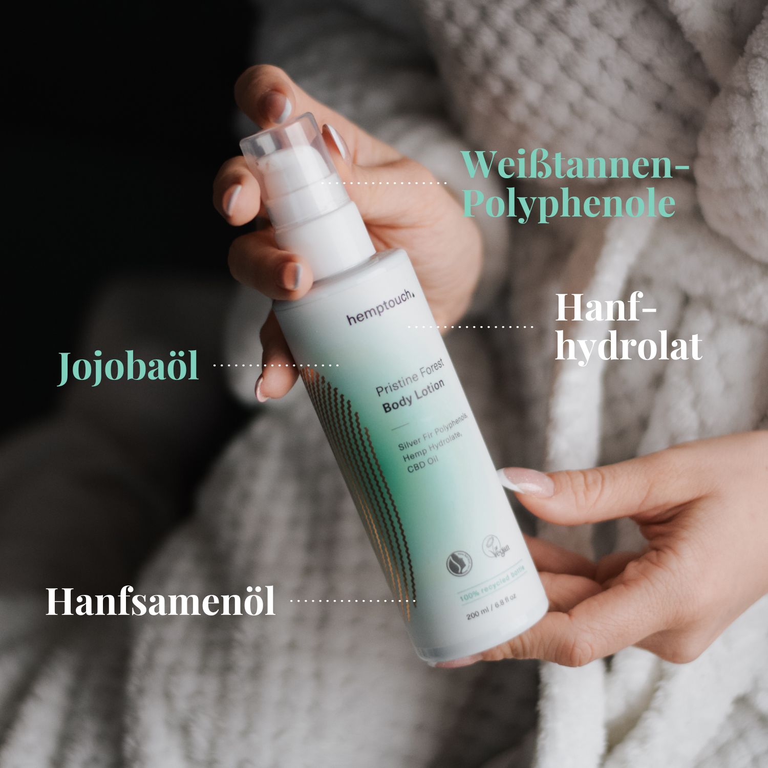 Frau hält eine weiße Lotionflasche mit Pumpspender, die Hände sind in einem Bademantel.