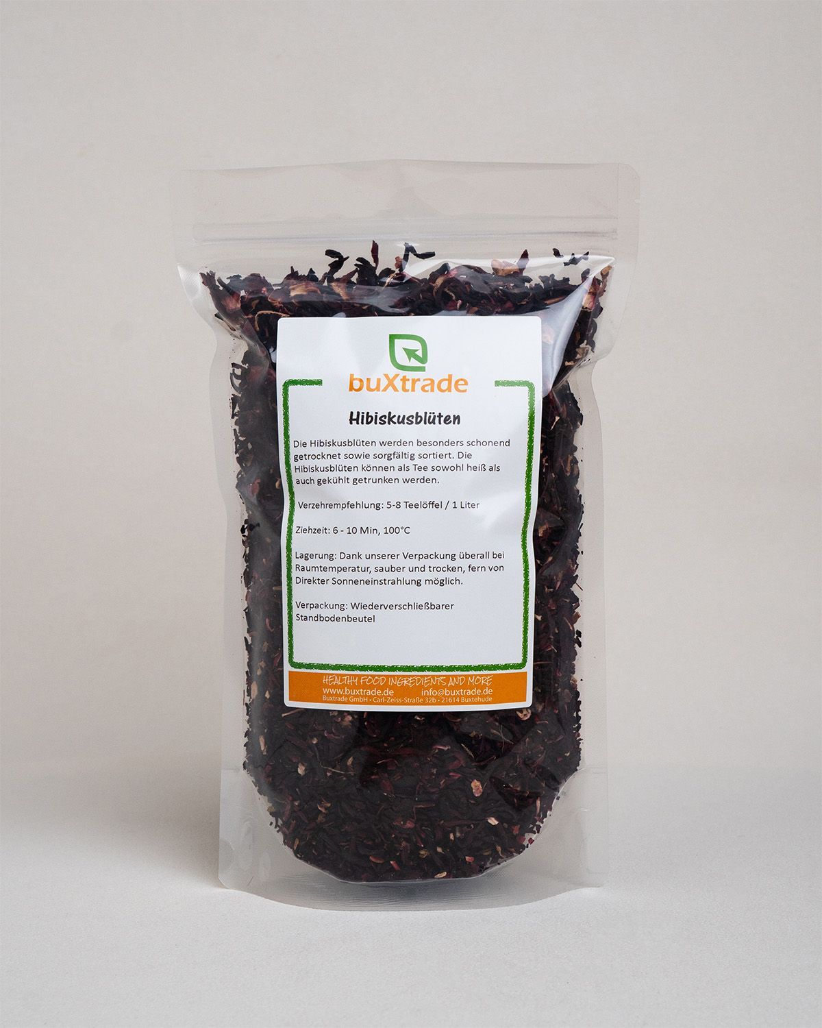 Transparenter Beutel gefüllt mit getrockneten Hibiskusblüten. Produktetikett mit Text: buXtrade Hibiskusblüten.