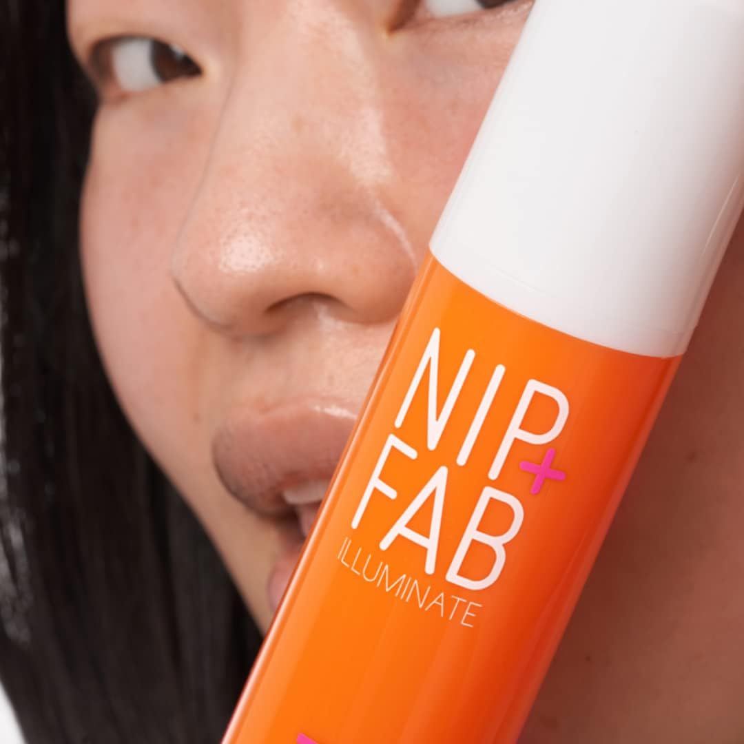 Nahaufnahme einer Person, die eine orangefarbene Flasche hält. Aufschrift: NIP+FAB, ILLUMINATE. Teilweise sichtbar: Gesicht.