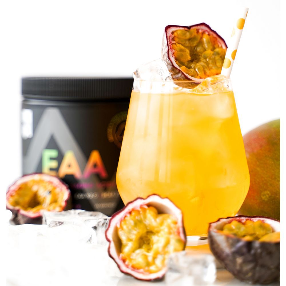 Glas mit gelbem Getränk, Eiswürfeln und Strohhalm. Dekoriert mit Passionsfrucht. Dose mit EAA-Aufschrift im Hintergrund.