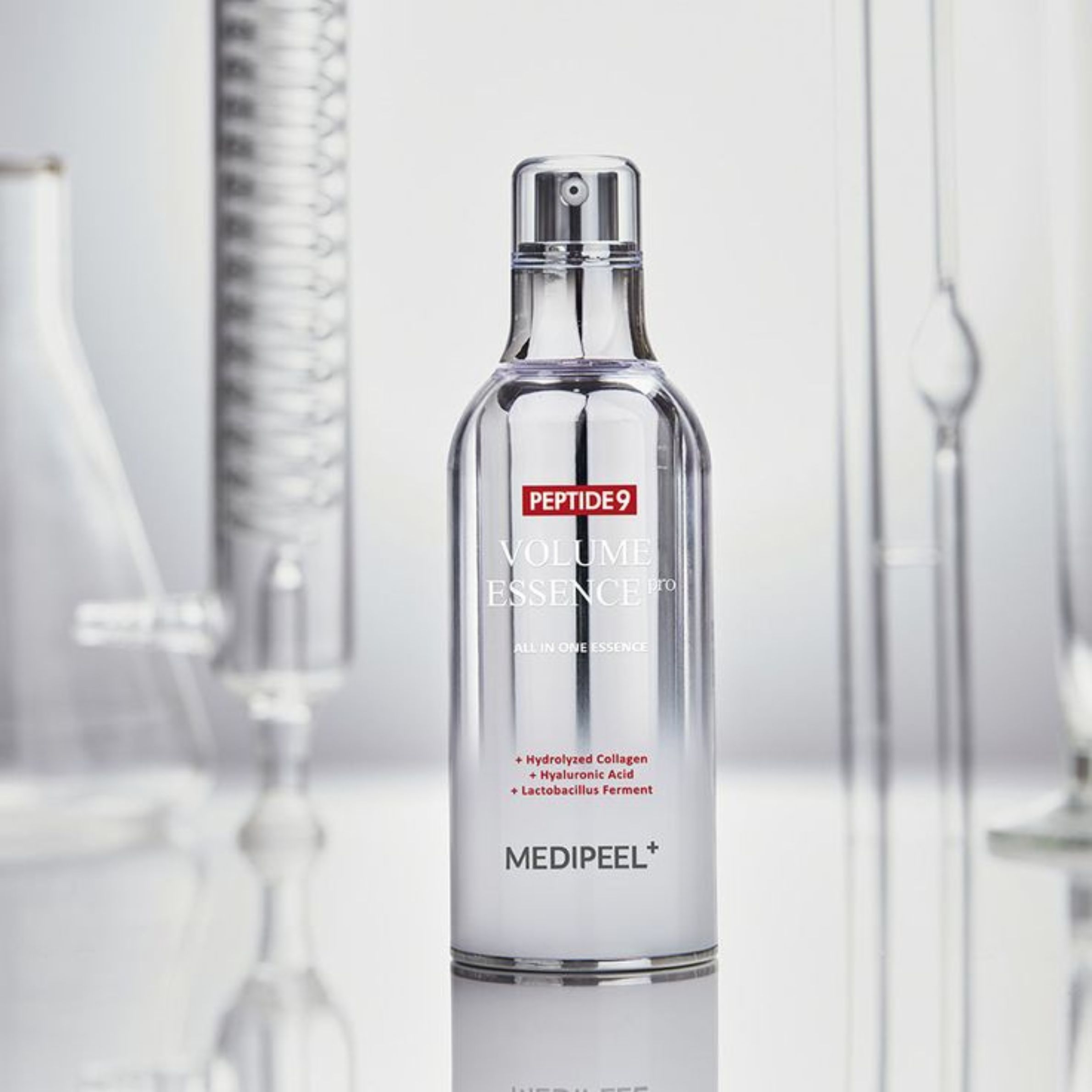 Medi-Peel Peptide 9 Volume Essence in silberner Flasche, umgeben von Laborgeräten. Enthält Hydrolyzed Collagen, Hyaluronic Acid.