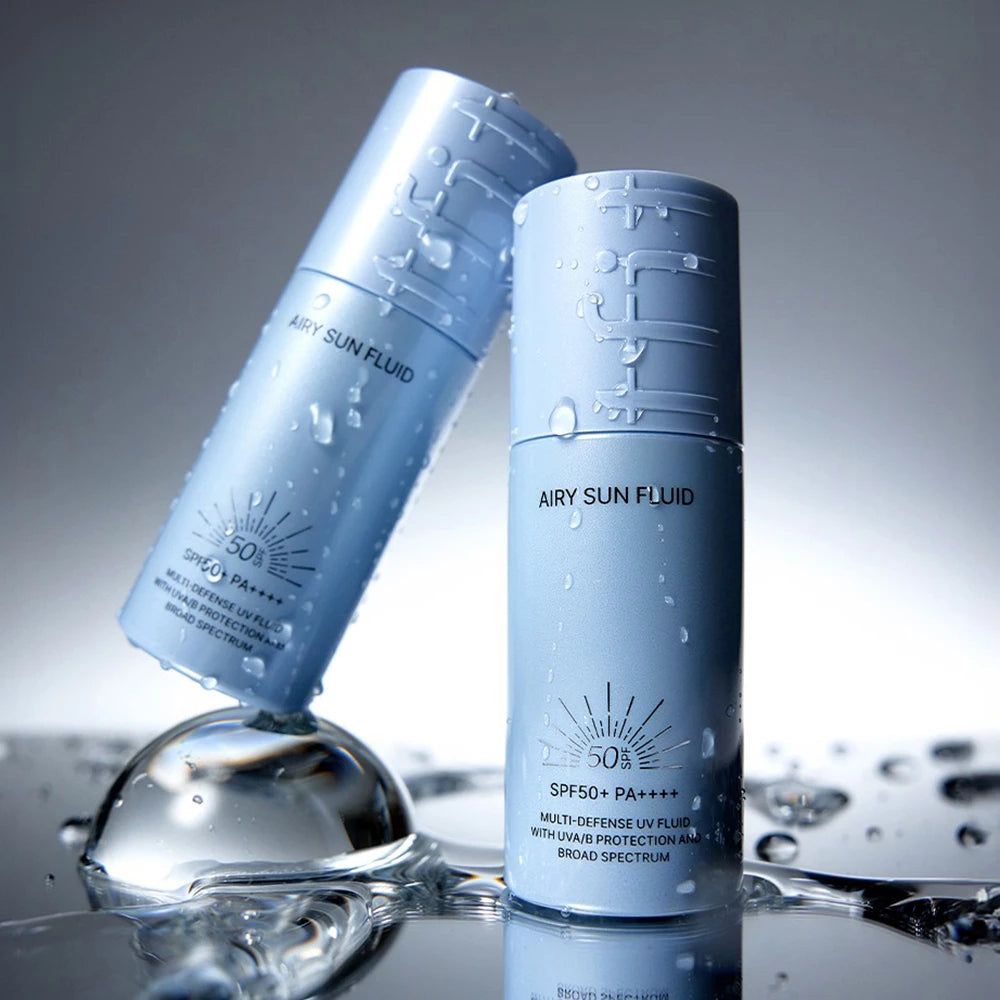 Zwei TFIT Airy Sun Fluid Flaschen auf nasser Oberfläche, mit Wassertropfen.