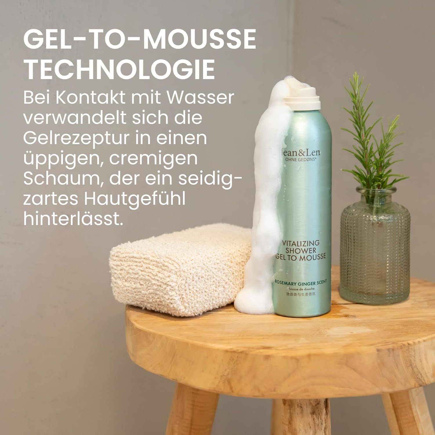 Grüne Sprühflasche mit weißem Deckel. Schaum tritt aus. Auf einem Holzhocker. Daneben ein Glas mit Rosmarinzweig.