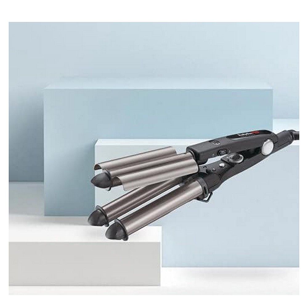 Babyliss Lockenstab mit drei Wellenstäben, platziert auf abstrakten geometrischen Formen.