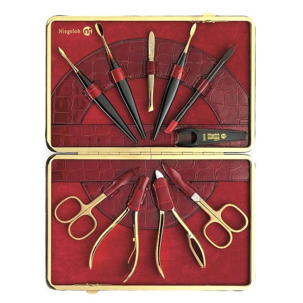 Offenes, rotes Etui mit goldenem Rahmen, gefüllt mit Maniküre-Werkzeugen. Enthält Scheren, Nagelhautschieber und -zangen. Marke Niegeloh.