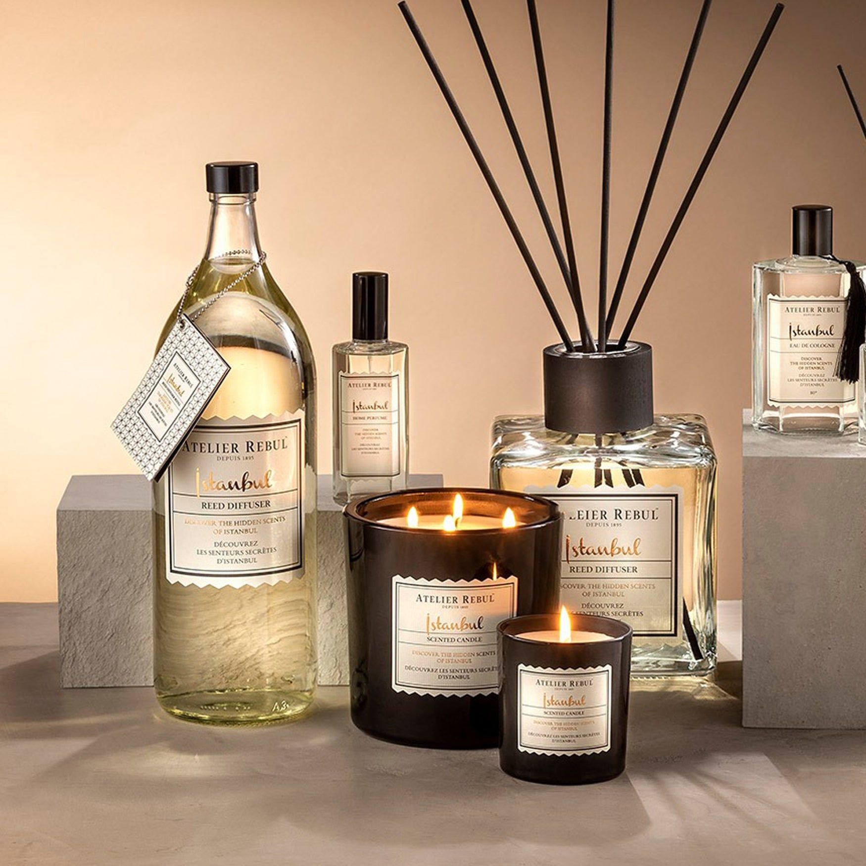 Verschiedene Produkte, darunter ein Kerzenglas und ein Diffusor mit Stäbchen. Alle tragen das Etikett "Atelier Rebul Istanbul".