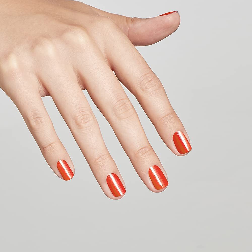 Hand mit lackierten Fingernägeln. Die Nägel sind mit orangefarbenem Nagellack lackiert. Helle Oberfläche.