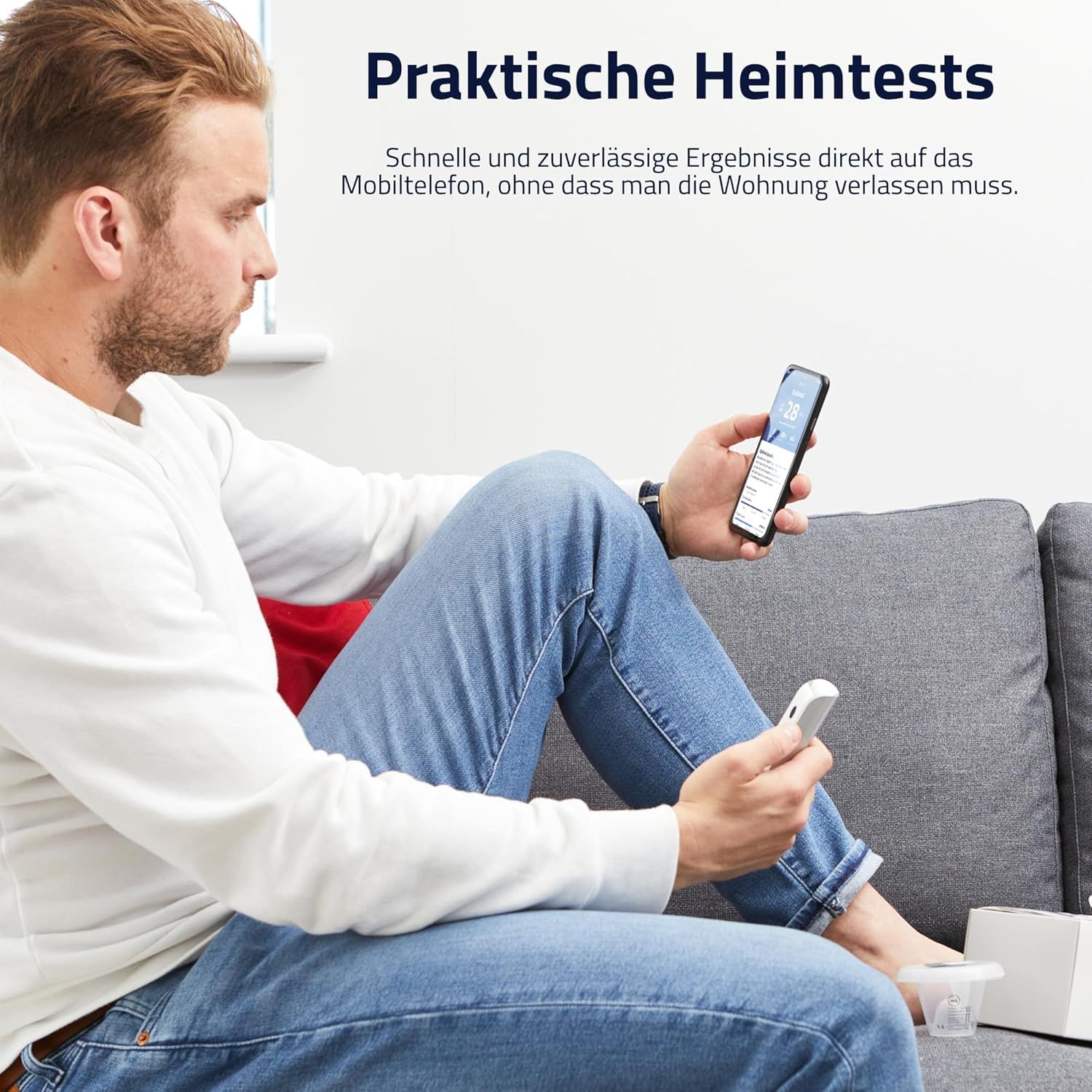 Mann sitzt auf Sofa, hält Smartphone und ExSeed-Gerät. Auf dem Smartphone ist eine App zu sehen.