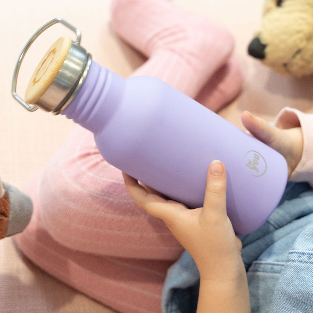 Kind hält lila Trinkflasche mit Bambusdeckel.