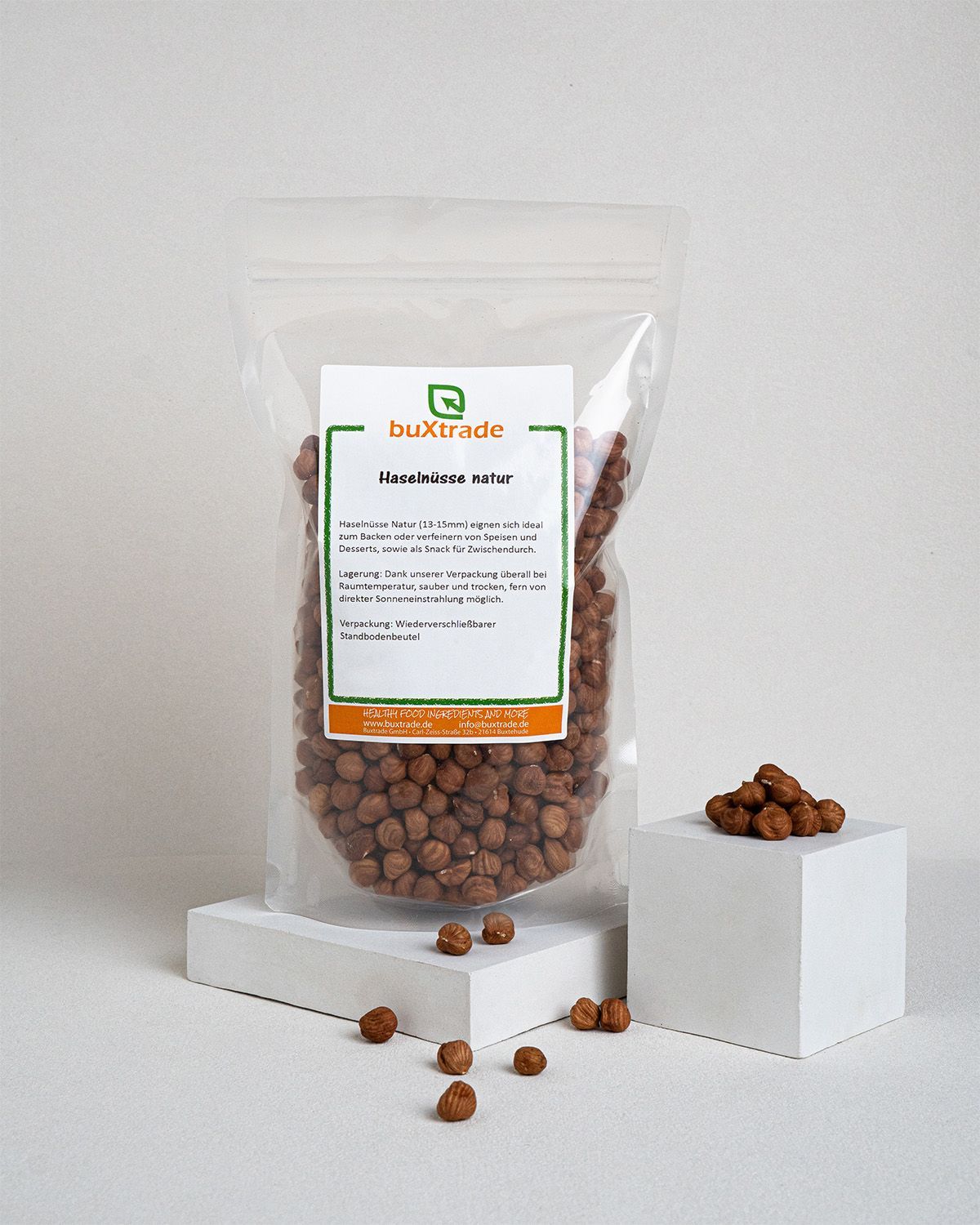 Transparente Tüte mit Haselnüssen und Podest. Aufdruck: buXtrade Haselnüsse Natur. Wiederverschließbar.
