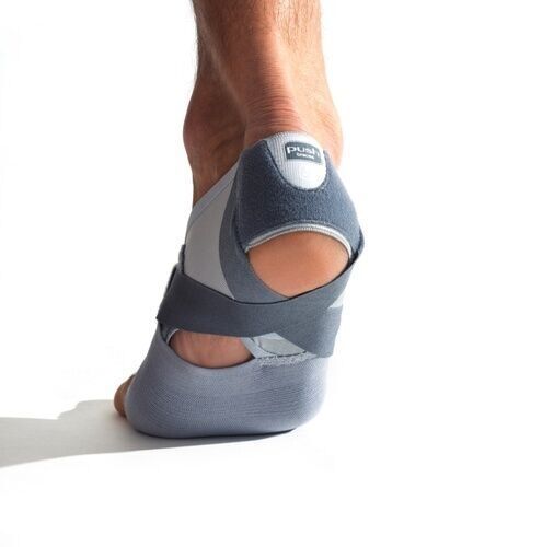 Rückansicht einer grau-blauen Fußbandage am Fuß. Der Fersenbereich ist offen. Das Produkt hat einen Klettverschluss und das Logo 'push'.