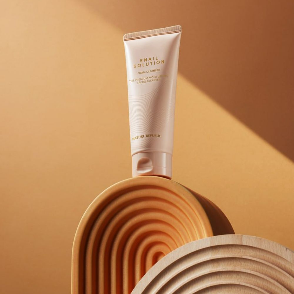 Beige Tube "Snail Solution Foam Cleanser" auf Holzstruktur. Text: "The Premium Moisturizing Facial Cleanser". Marke: NATURE REPUBLIC.