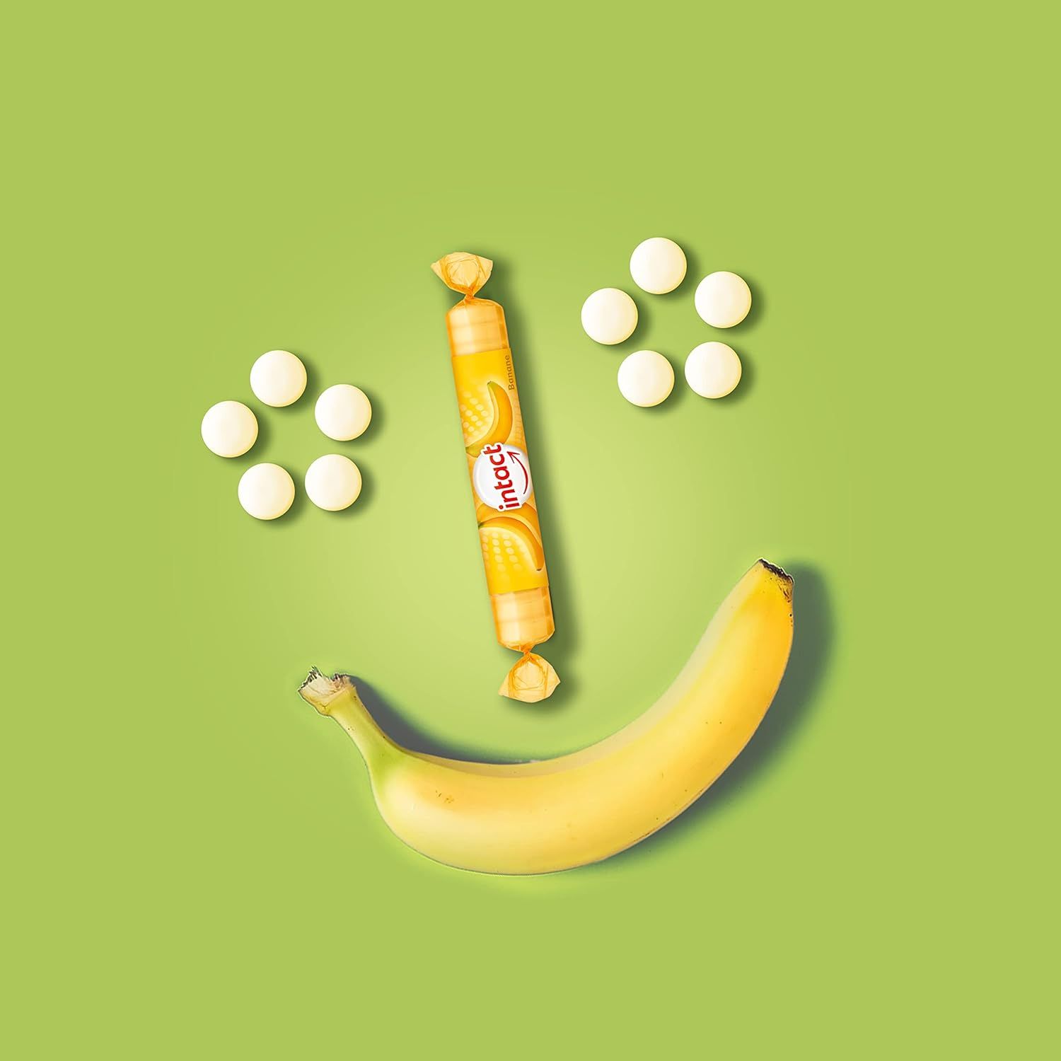 Ein Banane und Traubenzucker-Rolle, umgeben von Tabletten, bilden ein Smiley-Gesicht. Aufschrift: intact. Die Rolle hat ein Bananen-Design.