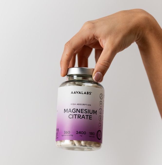 Hand hält eine Flasche Magnesiumcitrat-Kapseln.