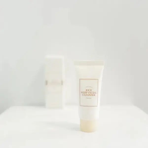 Weißer Tubenbehälter mit Aufschrift "Rice Whip Facial Cleanser". Dahinter ein rechteckiger Behälter. Beide auf weißem Untergrund.