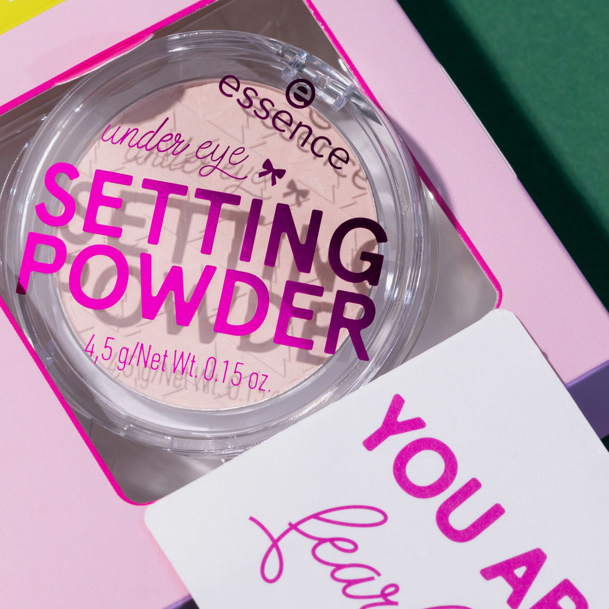 Runde Dose mit Setting Powder. Aufschrift « Setting Powder » und Markenlogo. Beilage mit Text. Steht auf einem grünen Hintergrund.