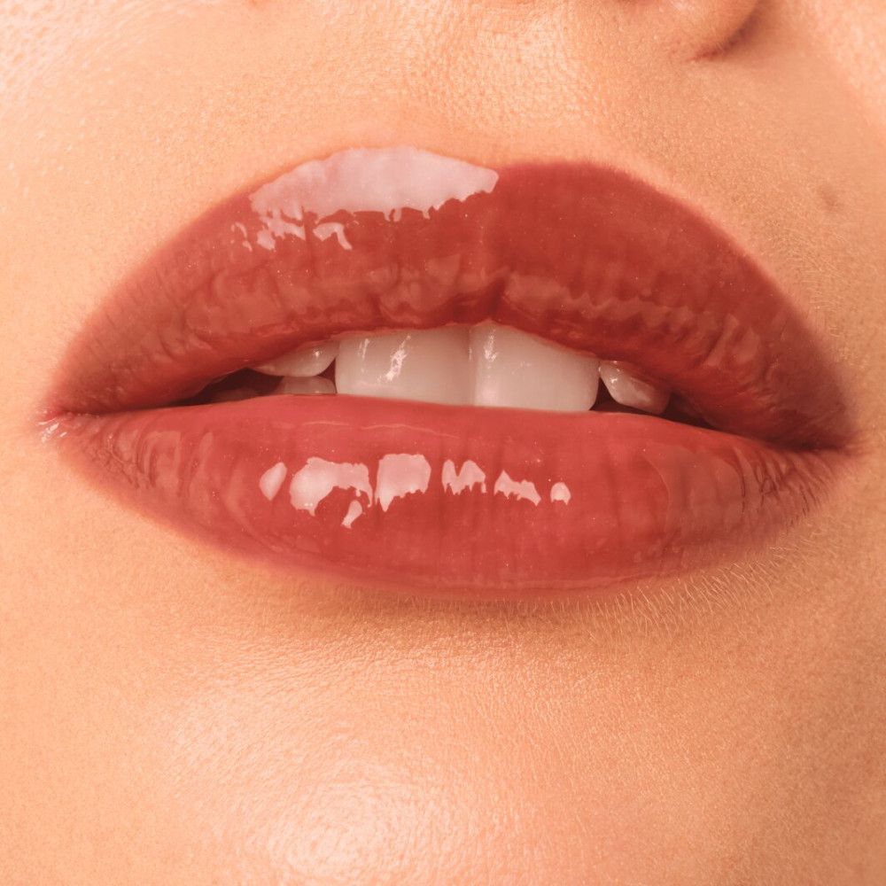 Nahaufnahme von Lippen mit glänzendem Lipgloss. Die Lippen sind rotbraun.