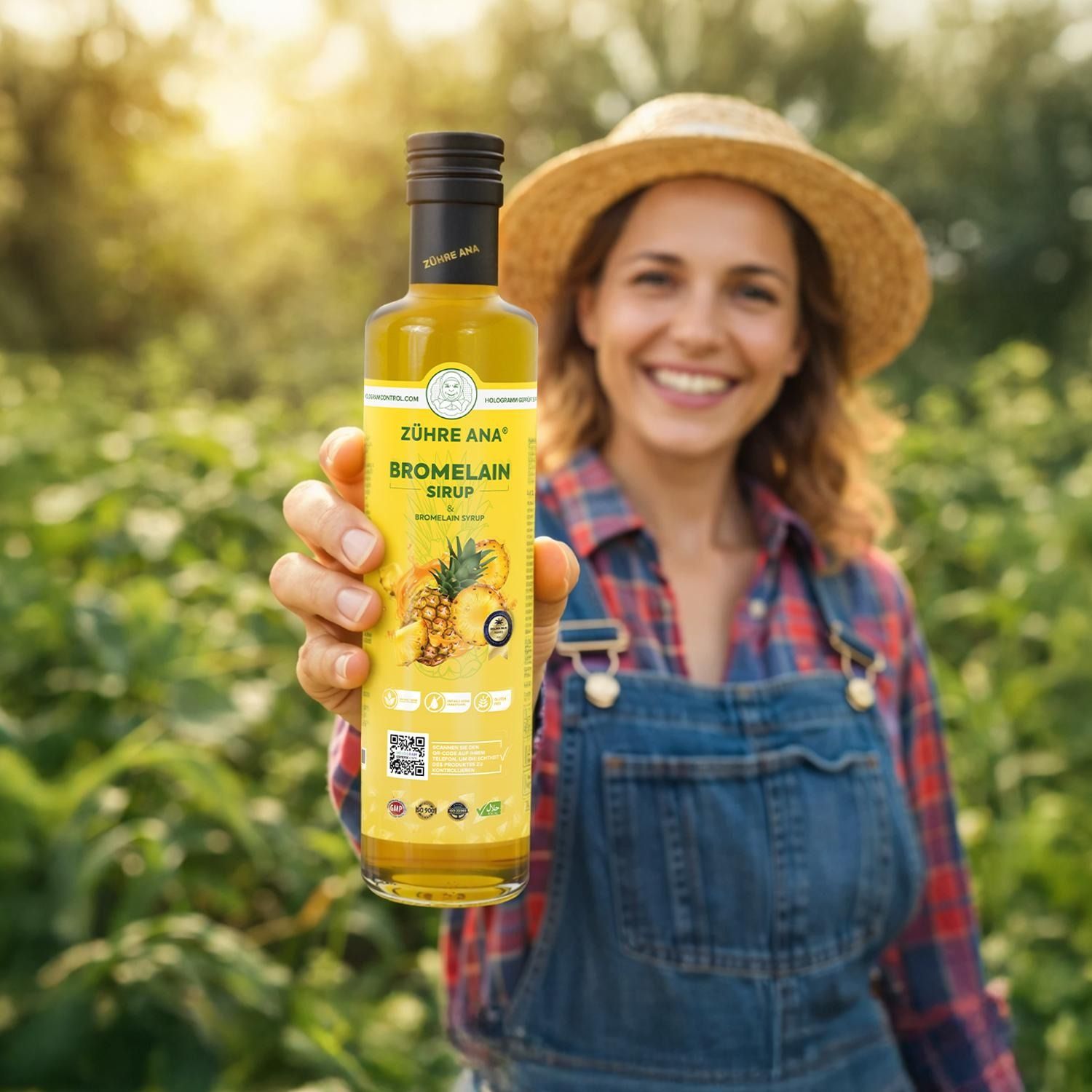 Frau mit Strohhut hält Flasche Zühre Ana Bromelain Sirup in einem Feld.