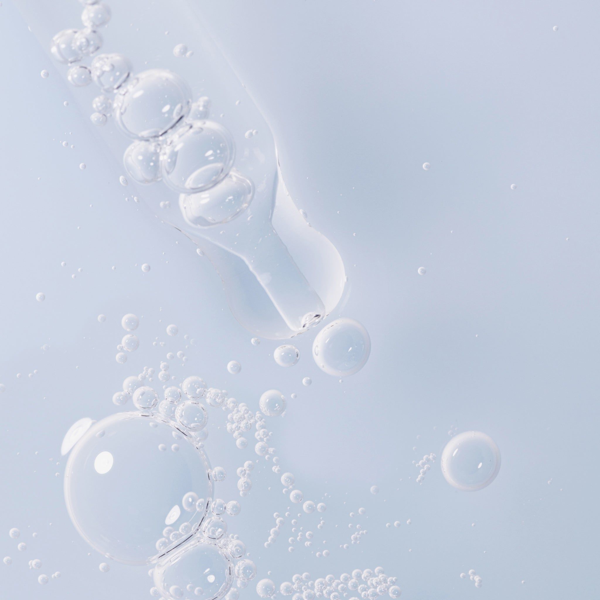 Nahaufnahme von Serumbläschen. Pipette mit Serumtröpfchen. Helle, blaue Flüssigkeit.