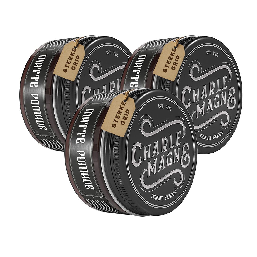 Drei schwarze Dosen mit Etiketten, die 'Matte Pomade' und 'Charles Magn&' zeigen.