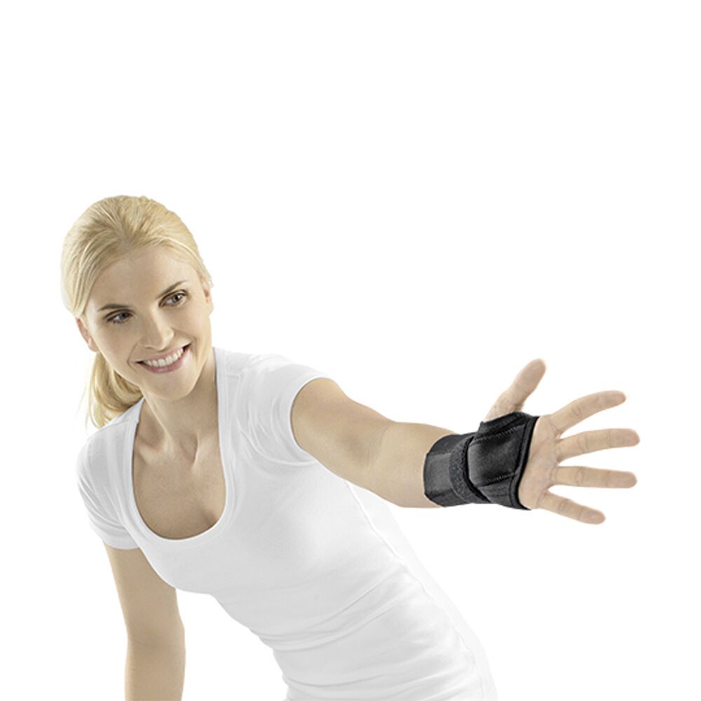 Handgelenkstütze am Handgelenk einer Frau. Schwarzes Material mit Klettverschluss. Frau mit weißem T-Shirt, Arm ausgestreckt.