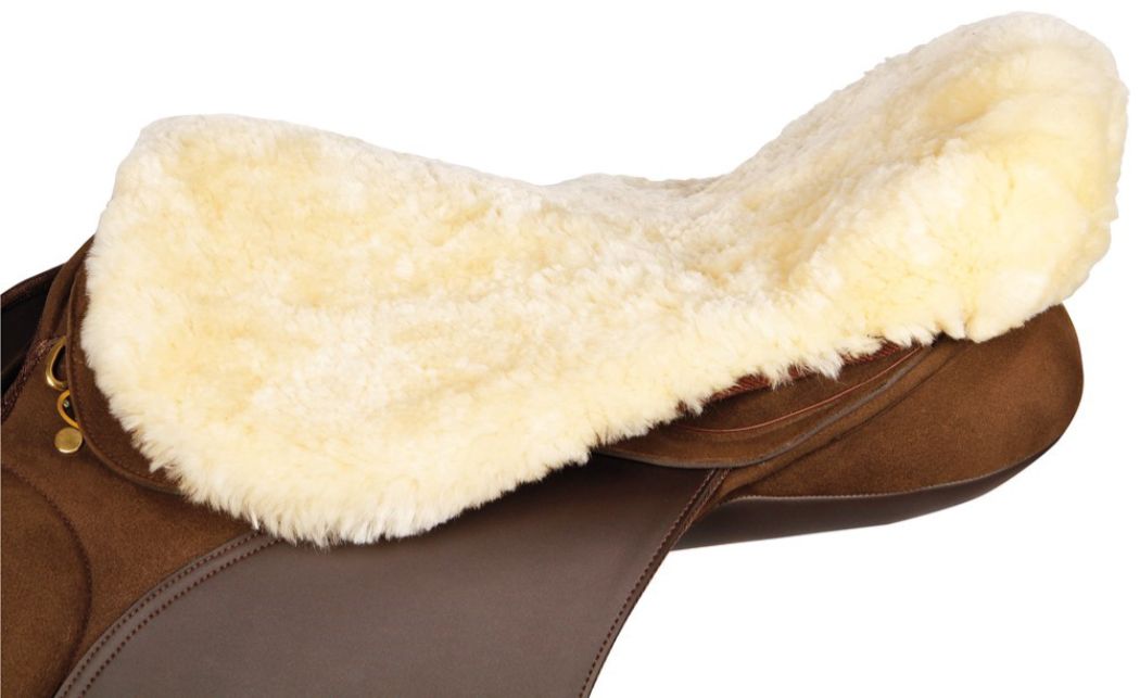 Beiger Lammfell Sattelsitzbezug auf einem braunen Sattel. Ansicht von der Seite.