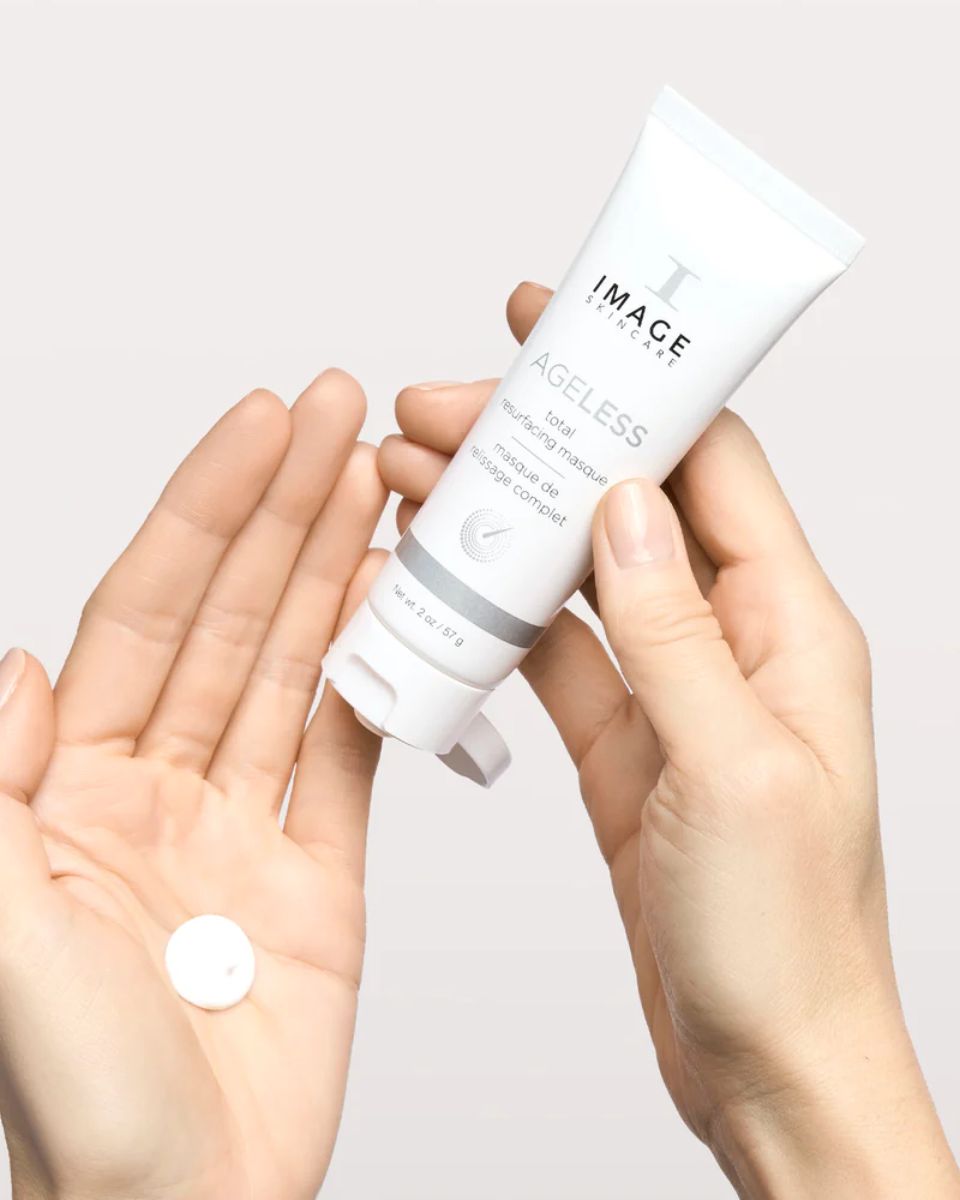 Hände halten eine Tube und eine Tablette. Tube: IMAGE Skincare, AGELESS total resurfacing masque.
