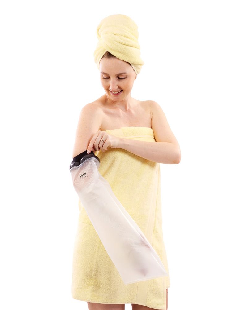 Person mit gelbem Handtuch und Armschutz. Der Armschutz ist transparent und hat einen schwarzen Abschluss. Das Produkt ist am Arm angebracht.
