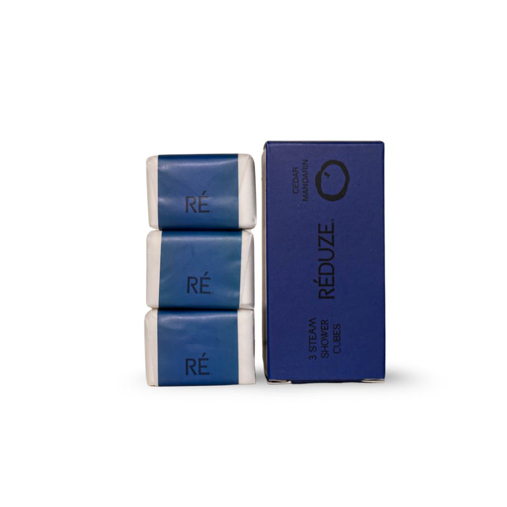 3 Duschwürfel und eine Box. Aufschrift: RÉ, 3 Steam Shower Cubes, Cedar Mandarin.