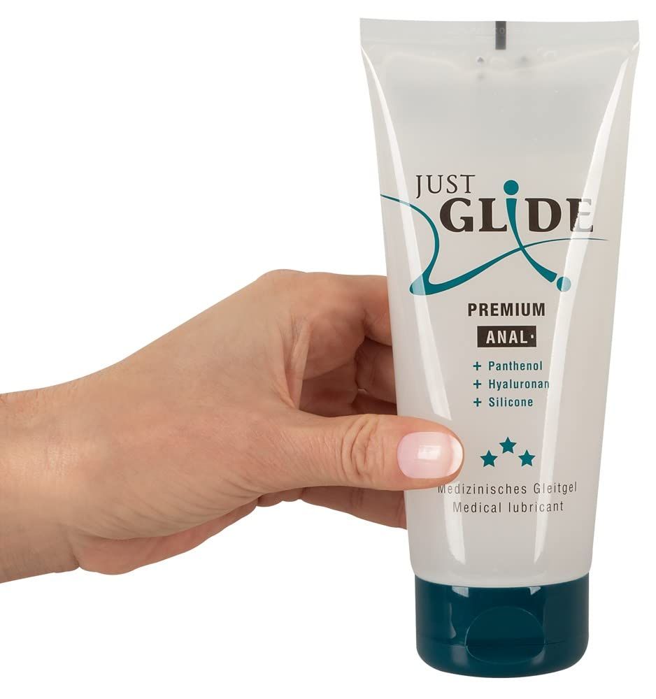 Hand hält Just Glide Premium Anal Gleitgel Tube. Transparenter Behälter mit blauem Verschluss.