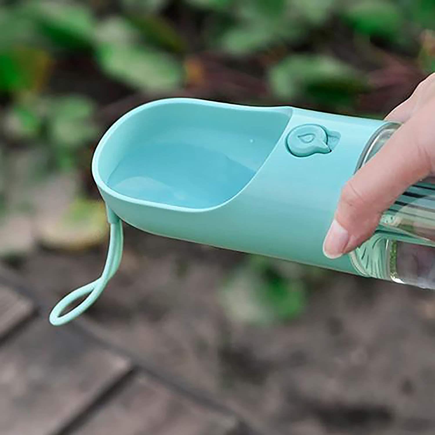Hand hält blaue Trinkschale mit Wasser. Schlaufe am Rand. Hintergrund unscharf.