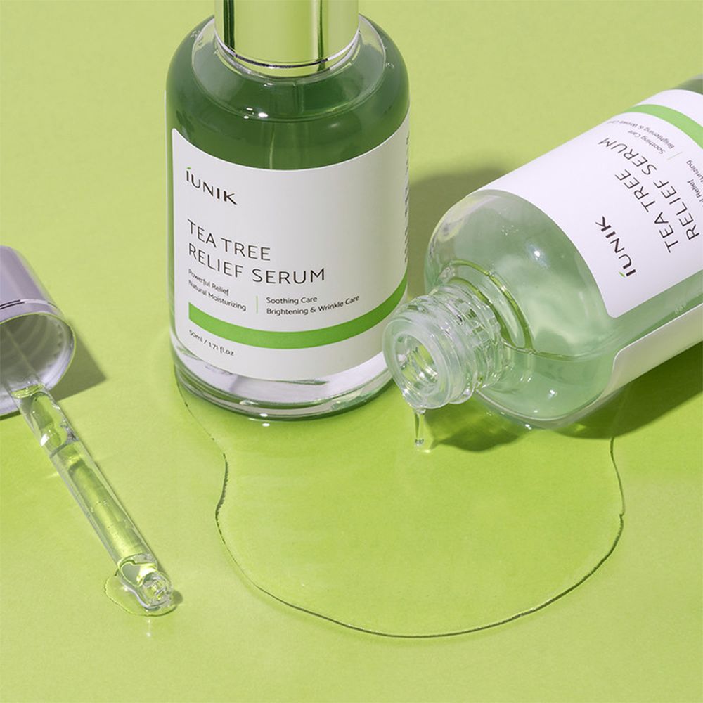 Zwei iUNIK Tea Tree Relief Serum Flaschen, eine liegt umgekippt mit verschüttetem Serum.