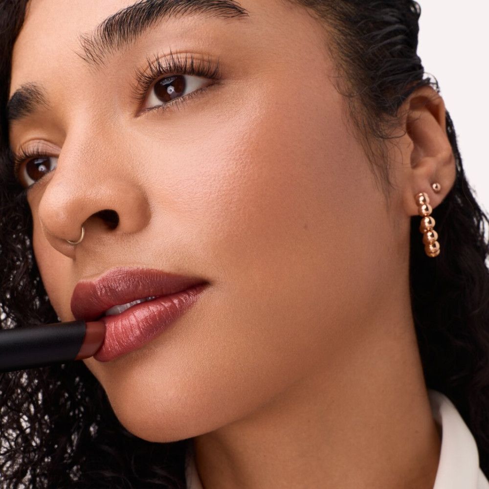 Frau trägt Lippenstift auf. Lippenstift in dunklem Farbton. Schwarzer Lippenstift-Stick.