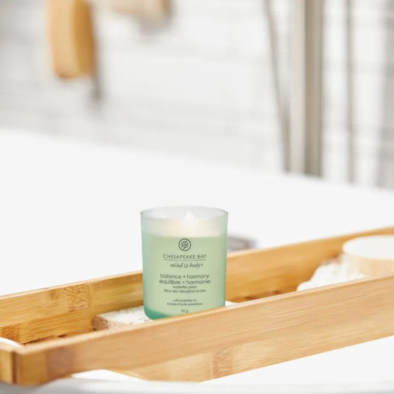 Kerze in Glasbehälter. Aufschrift: Chesapeake Bay, mind & body, balance + harmony, équilibre + harmonie. Auf Holzablage.