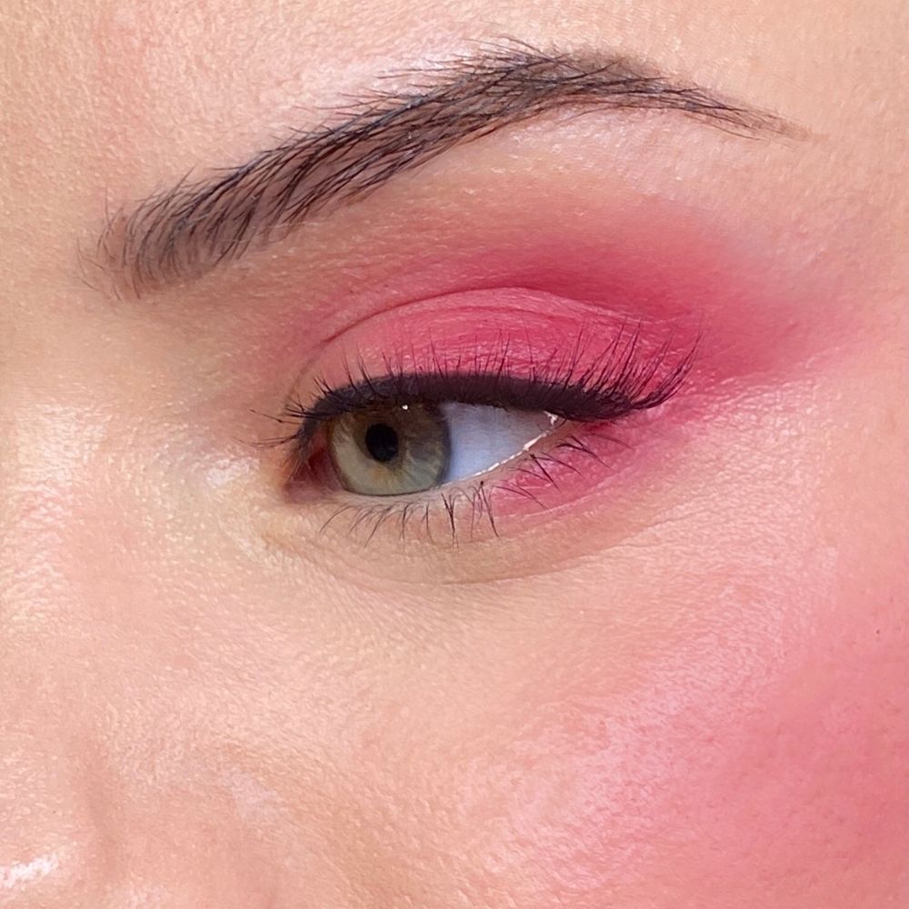 Nahaufnahme eines Auges mit rosa Make-up. Rosa Lidschatten und Rouge. Grünes Auge.
