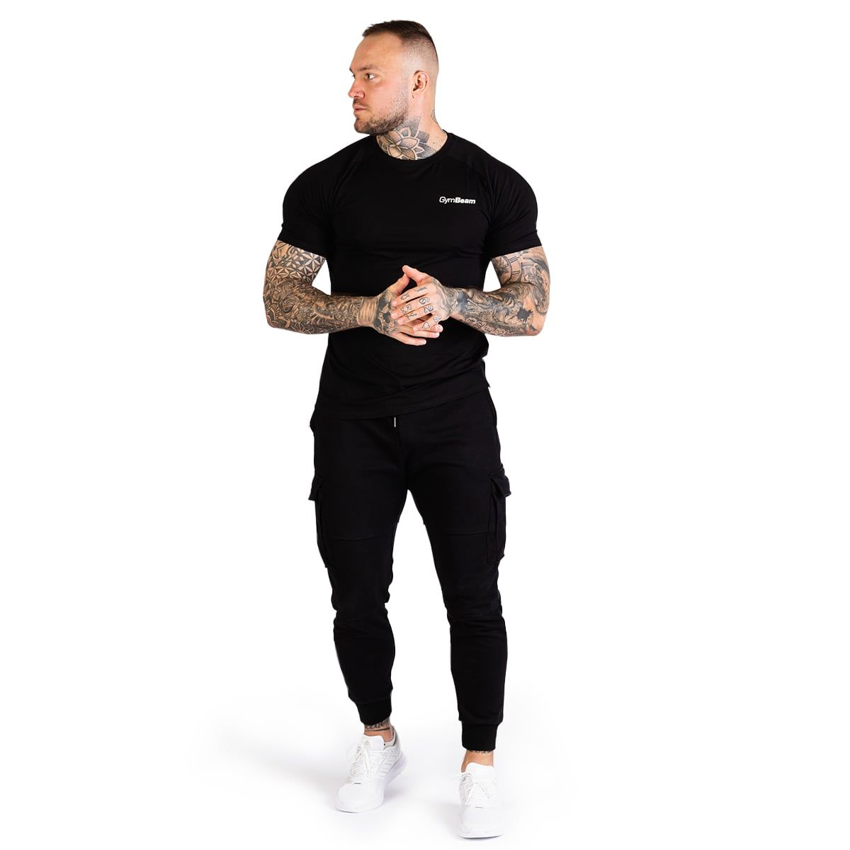 Ein Mann steht in voller Länge und trägt ein schwarzes Slim Fit T-Shirt und Cargohosen.