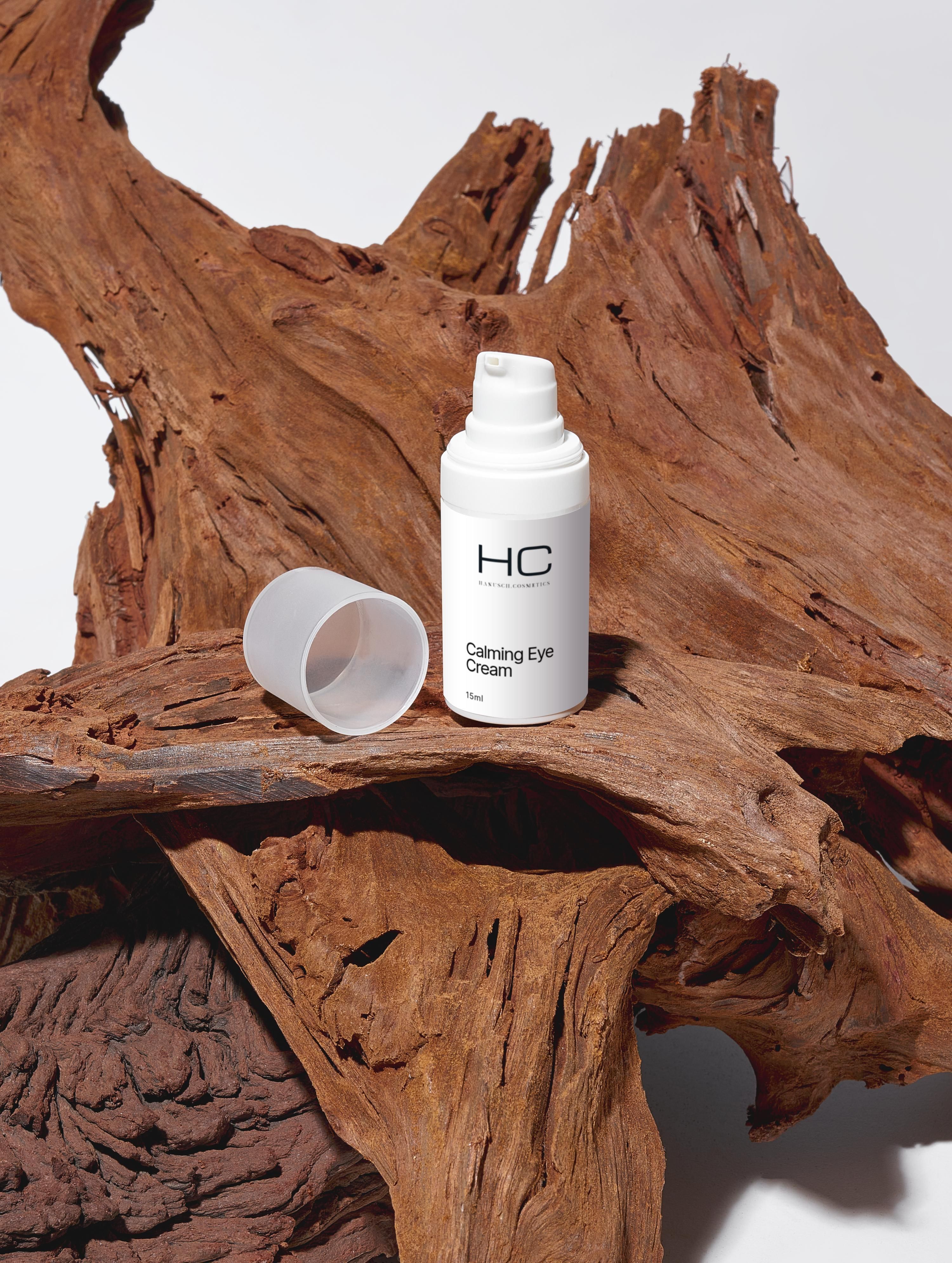 Weiße Flasche "HC Calming Eye Cream" mit geöffnetem Deckel. Auf Holz platziert.