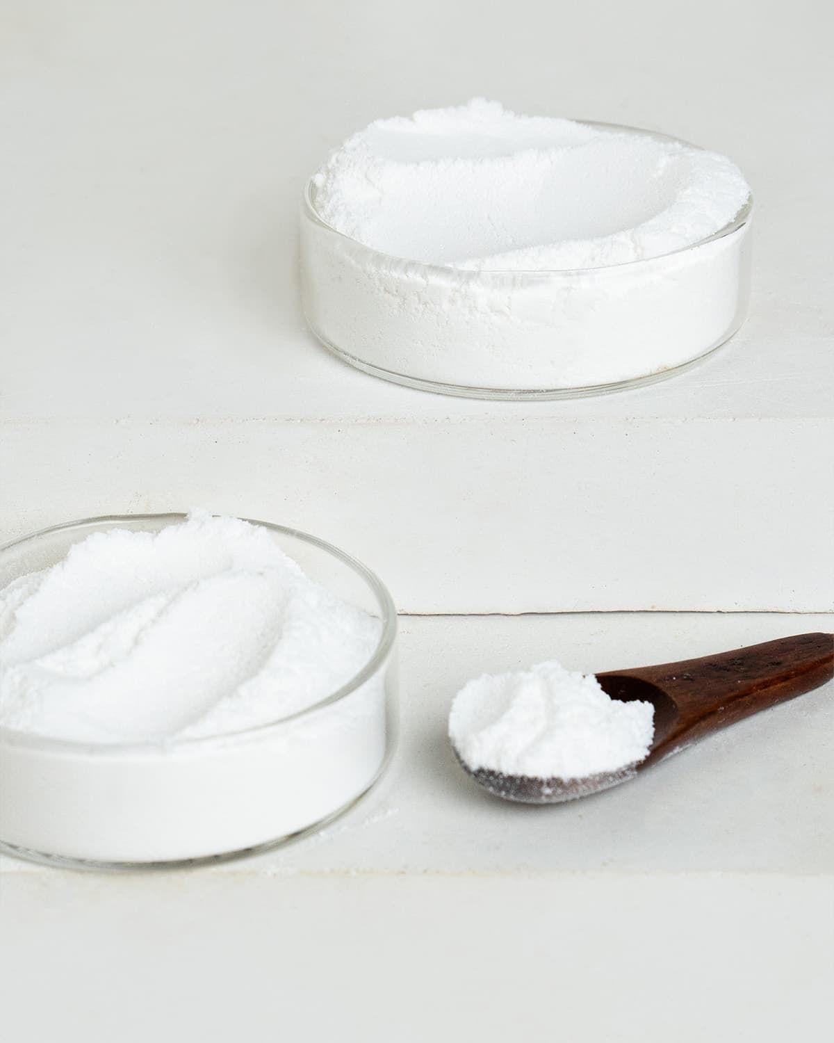 L-Phenylalanin Pulver in zwei Glasschalen und einem Holzlöffel.