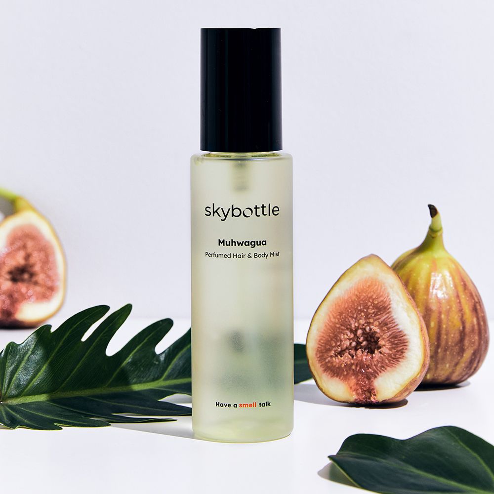 Flakon, Feigen und Blatt. Flakon: skybottle Muhwagua Perfumed Hair & Body Mist. Feigen: rosa Fruchtfleisch, grüne Schale. Blatt: grün.