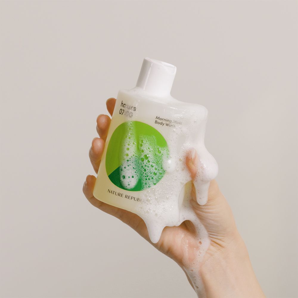 Hand hält Flasche mit Schaum. Flasche mit grünem Kreis und Text. Produkt: Morning Moss Body Wash. Marke: NATURE REPUBLIC.