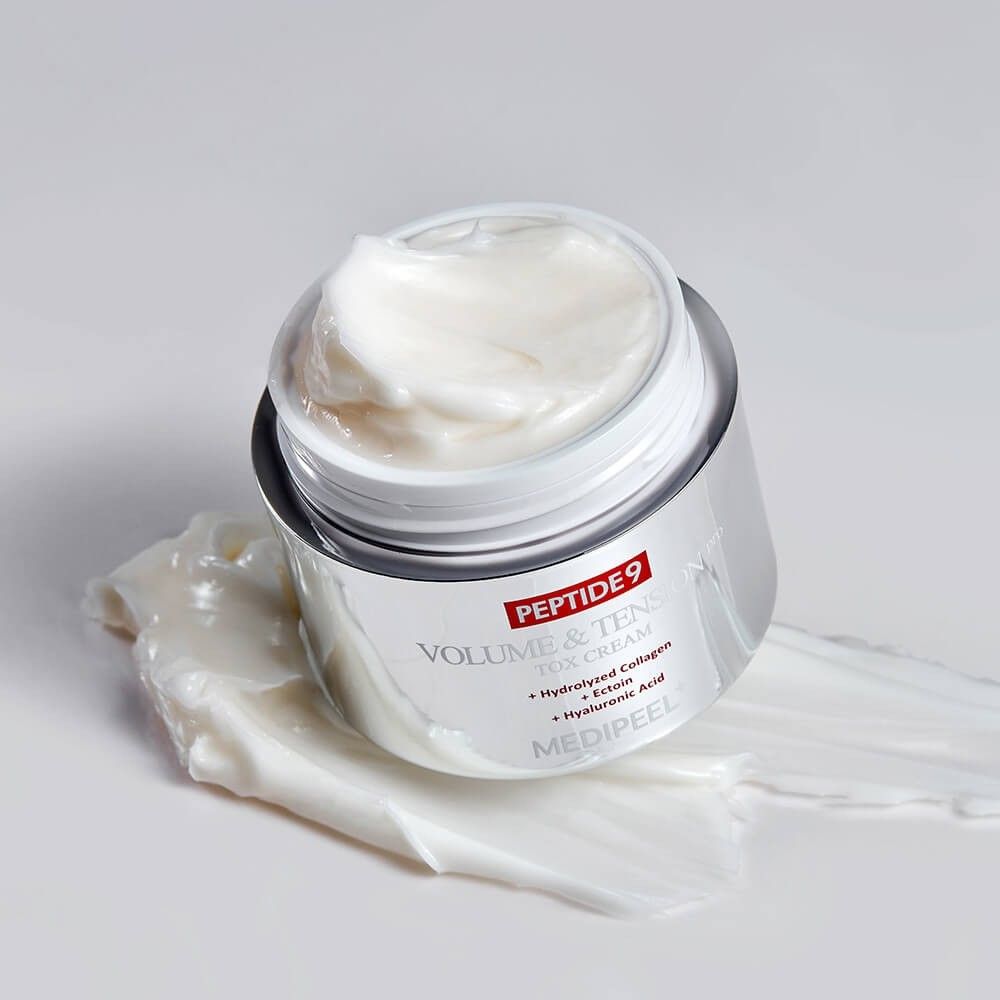 Offener Cremebehälter mit silbernem Körper, gefüllt mit weißer Creme. Creme ist auf der Oberfläche verteilt.