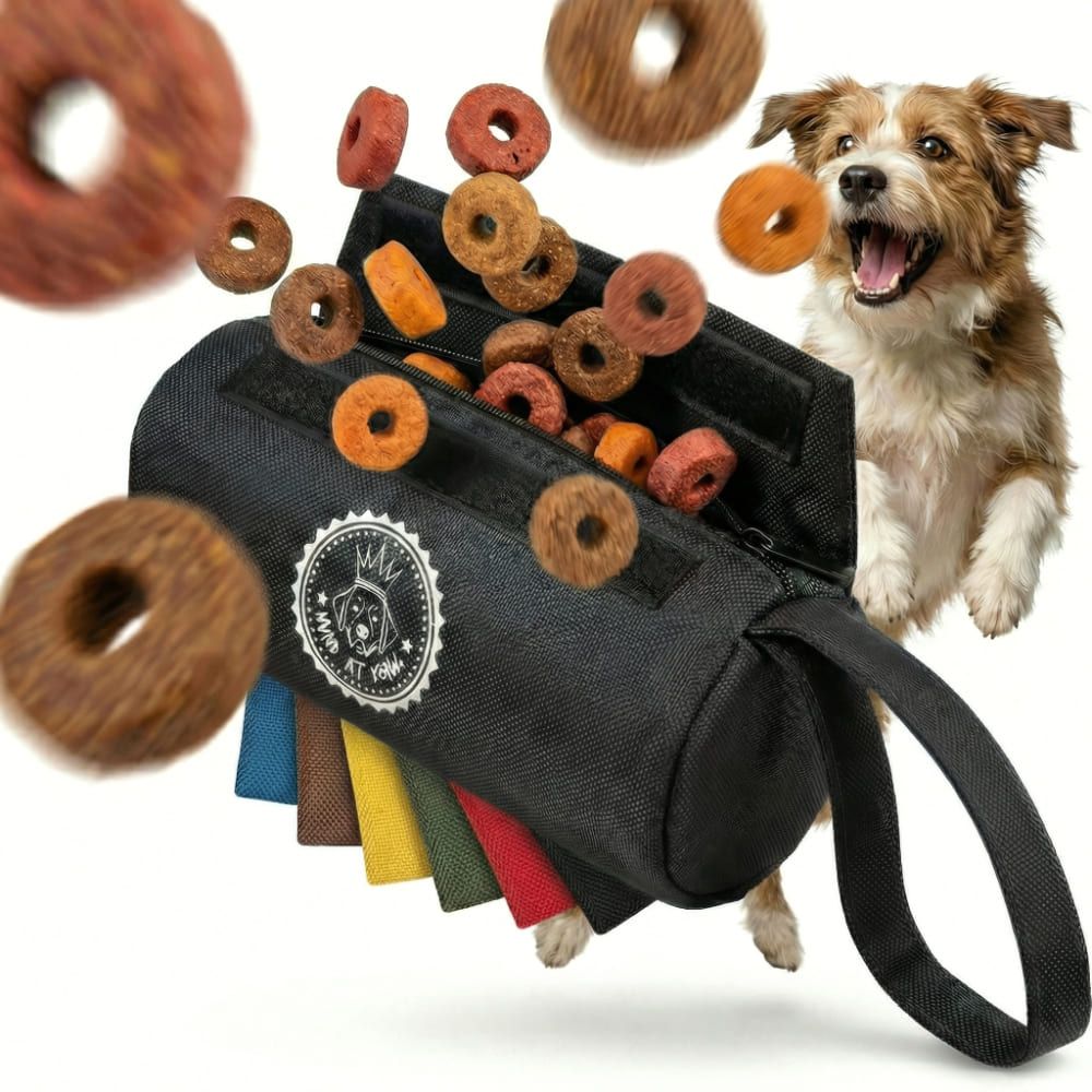 Schwarzer Futterbeutel mit Handschlaufe und Logo. Mehrere farbige Bänder am Boden. Hundefutter fliegt heraus. Hund schaut aufgeregt.