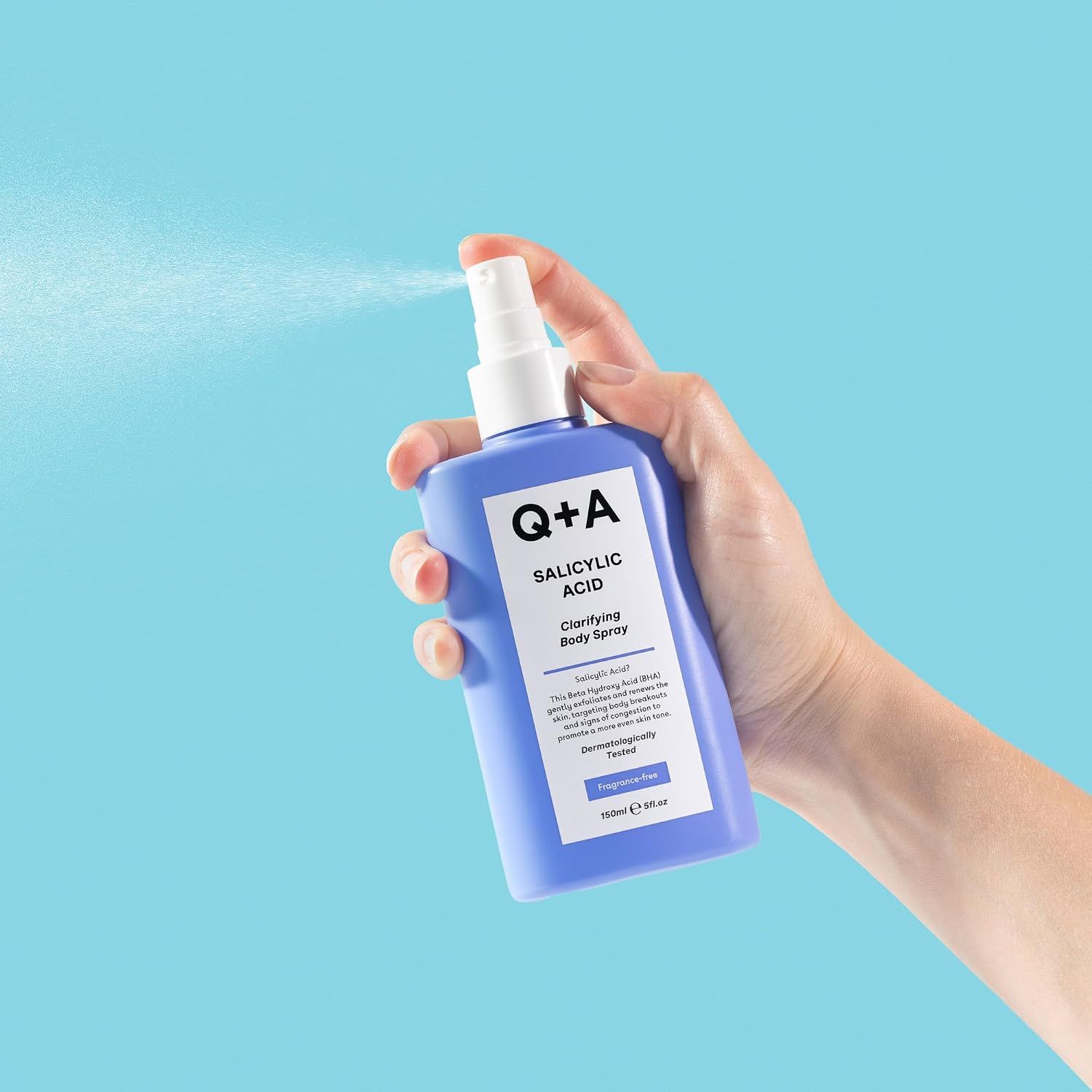 Hand hält Q+A Salicylic Acid Clarifying Body Spray, sprüht leicht.