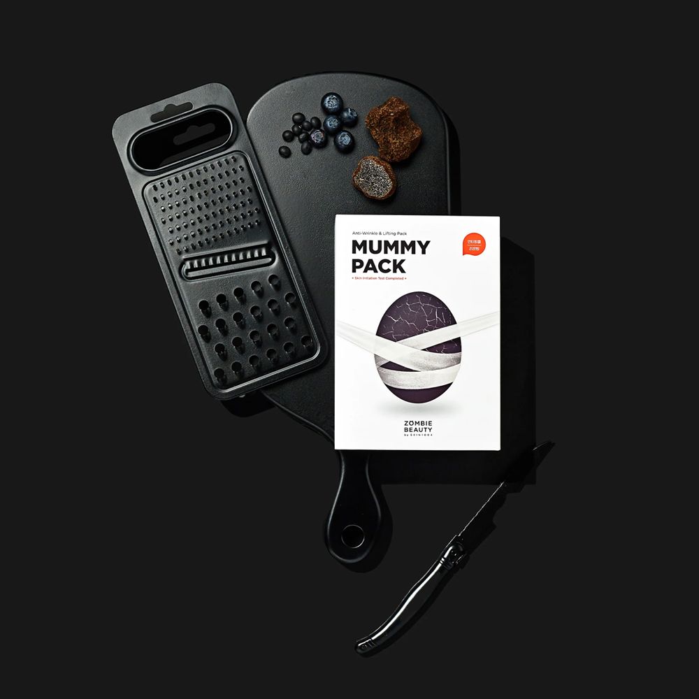 Schwarzes Schneidebrett mit Zutaten und Produktpackung. Aufdruck: MUMMY PACK.