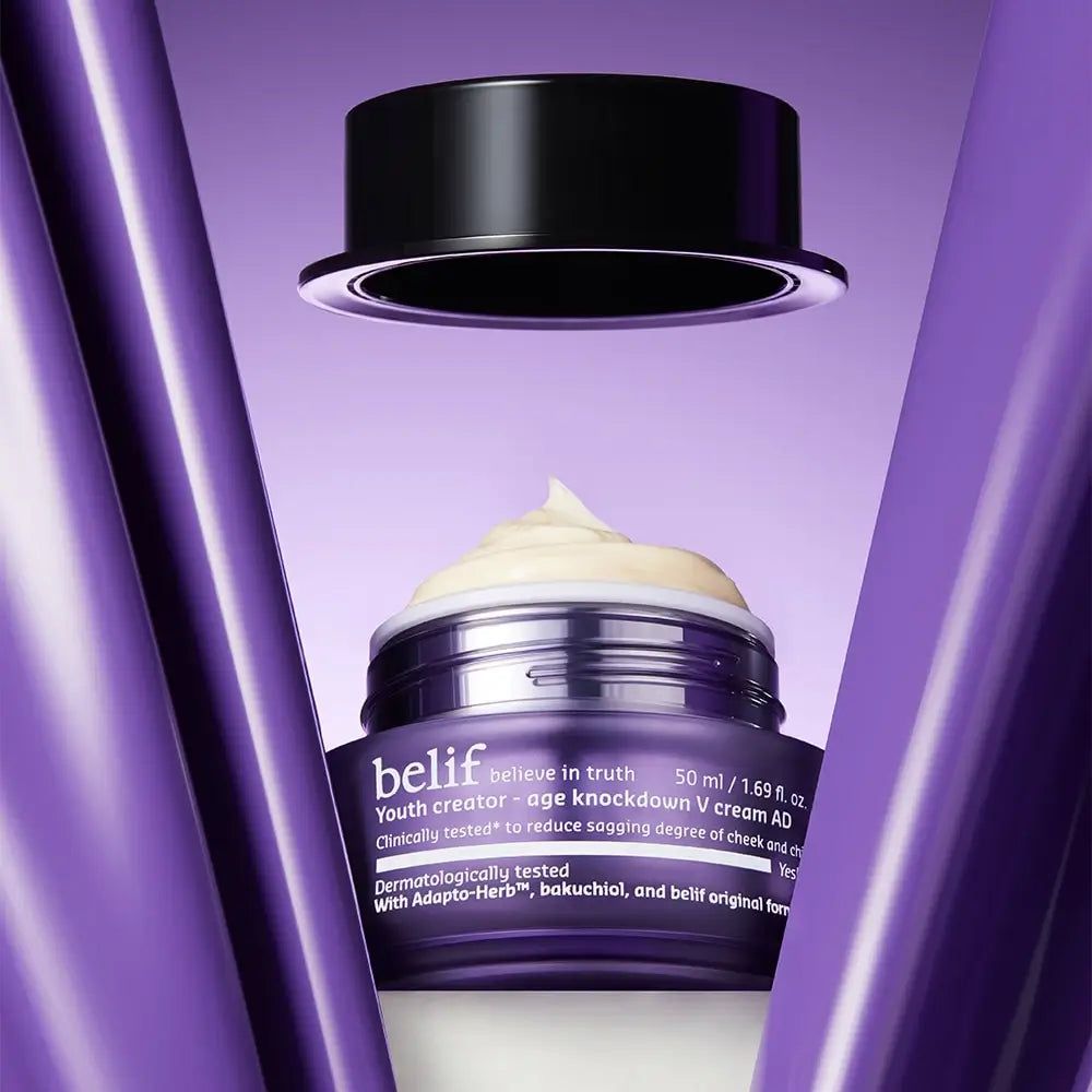 Belif Youth Creator Age Knockdown V Cream in einem offenen violetten Tiegel mit schwarzem Deckel darüber.