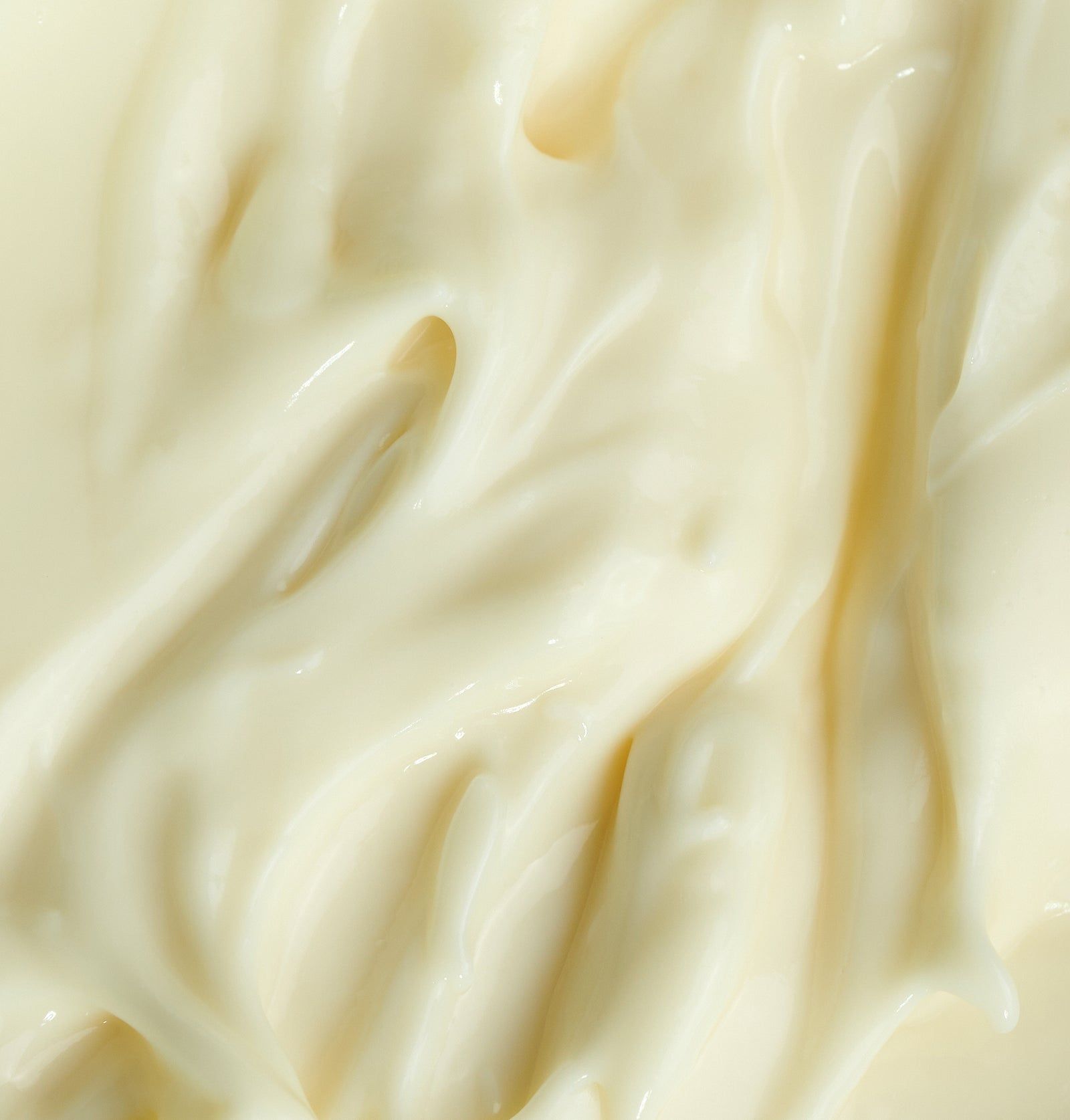 Nahaufnahme von Creme. Die Creme ist hell und hat eine glatte, gewellte Oberfläche.