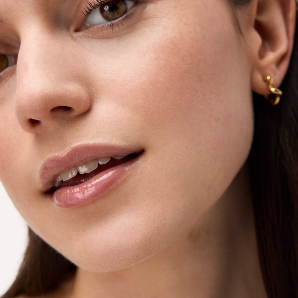 Nahaufnahme eines Gesichts mit glänzenden Lippen. Lip Elixir auf den Lippen.