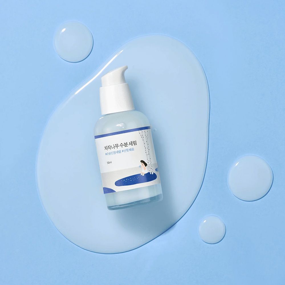 Round Lab Birch Juice Serum, 50ml, auf einem blauen Gel-Klecks mit Tropfen. Pumpspender.